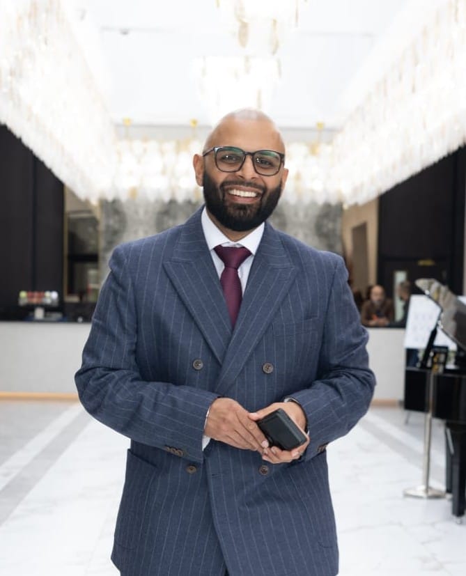 The Host Master UK in a navy double-breasted suit, hosting at a luxury venue